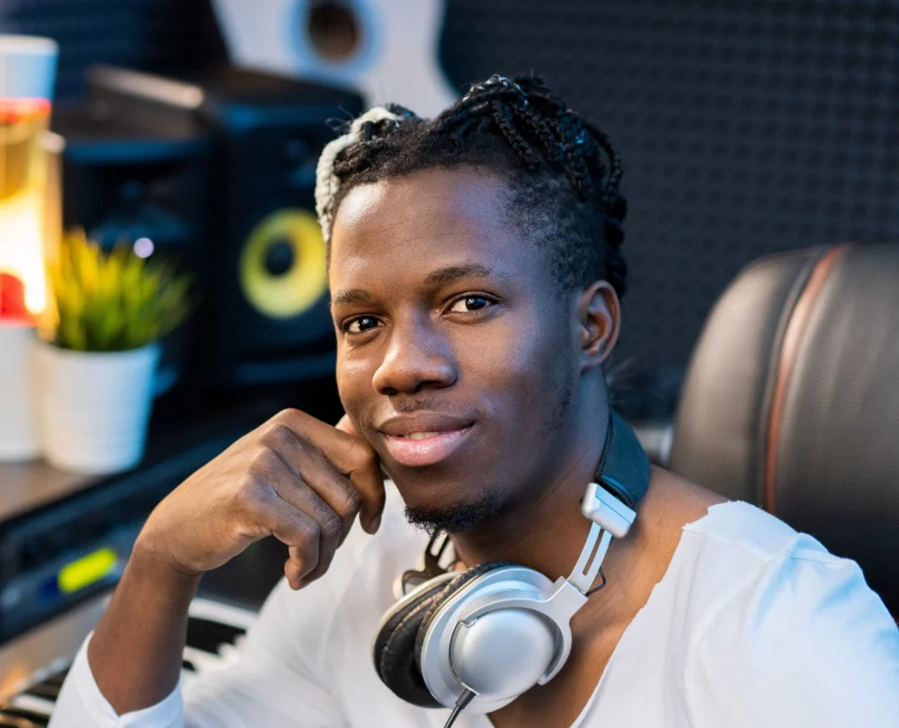 man with headphones on neck in front of studio computer